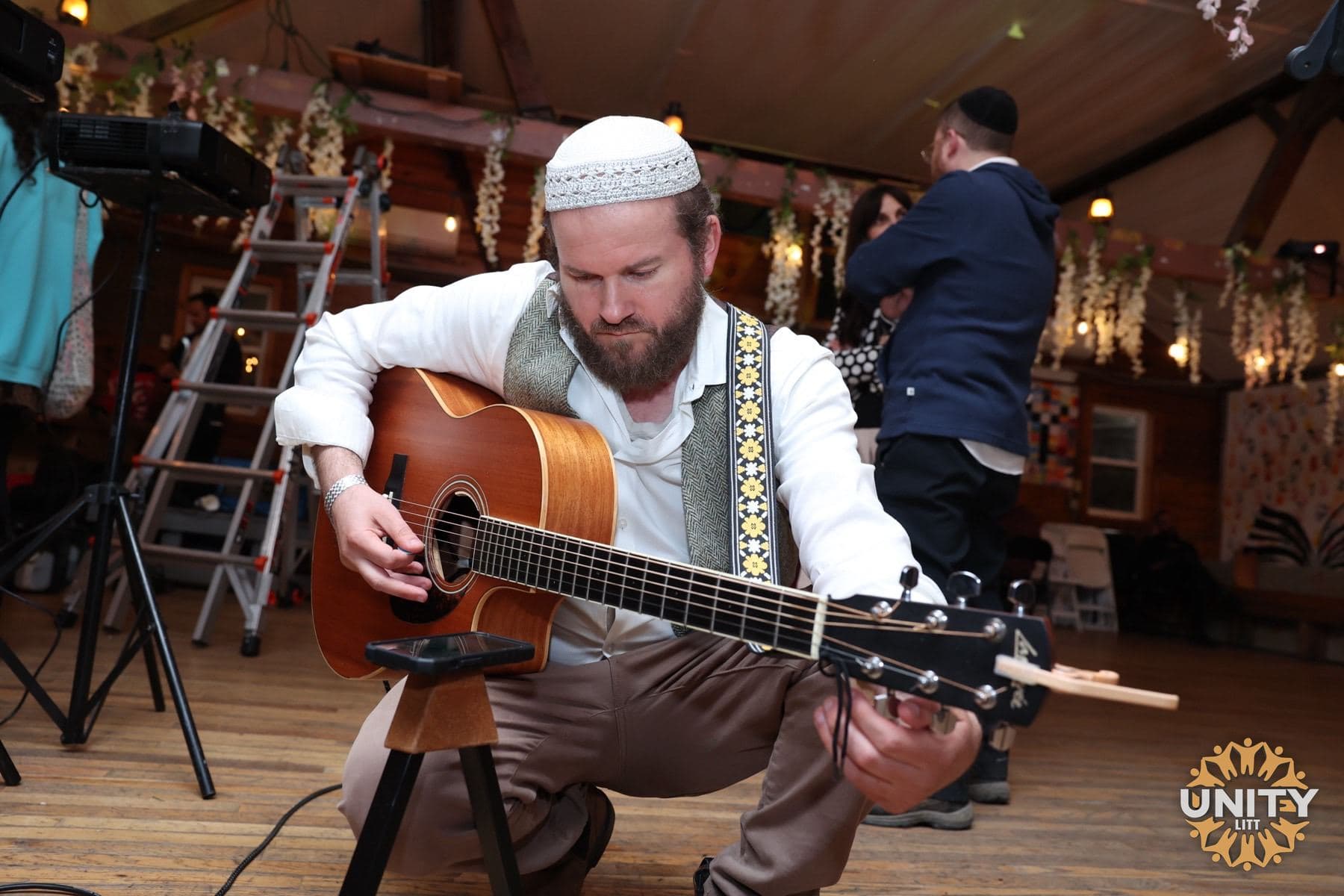 A guitarist playing to the room, warm lights strung behind