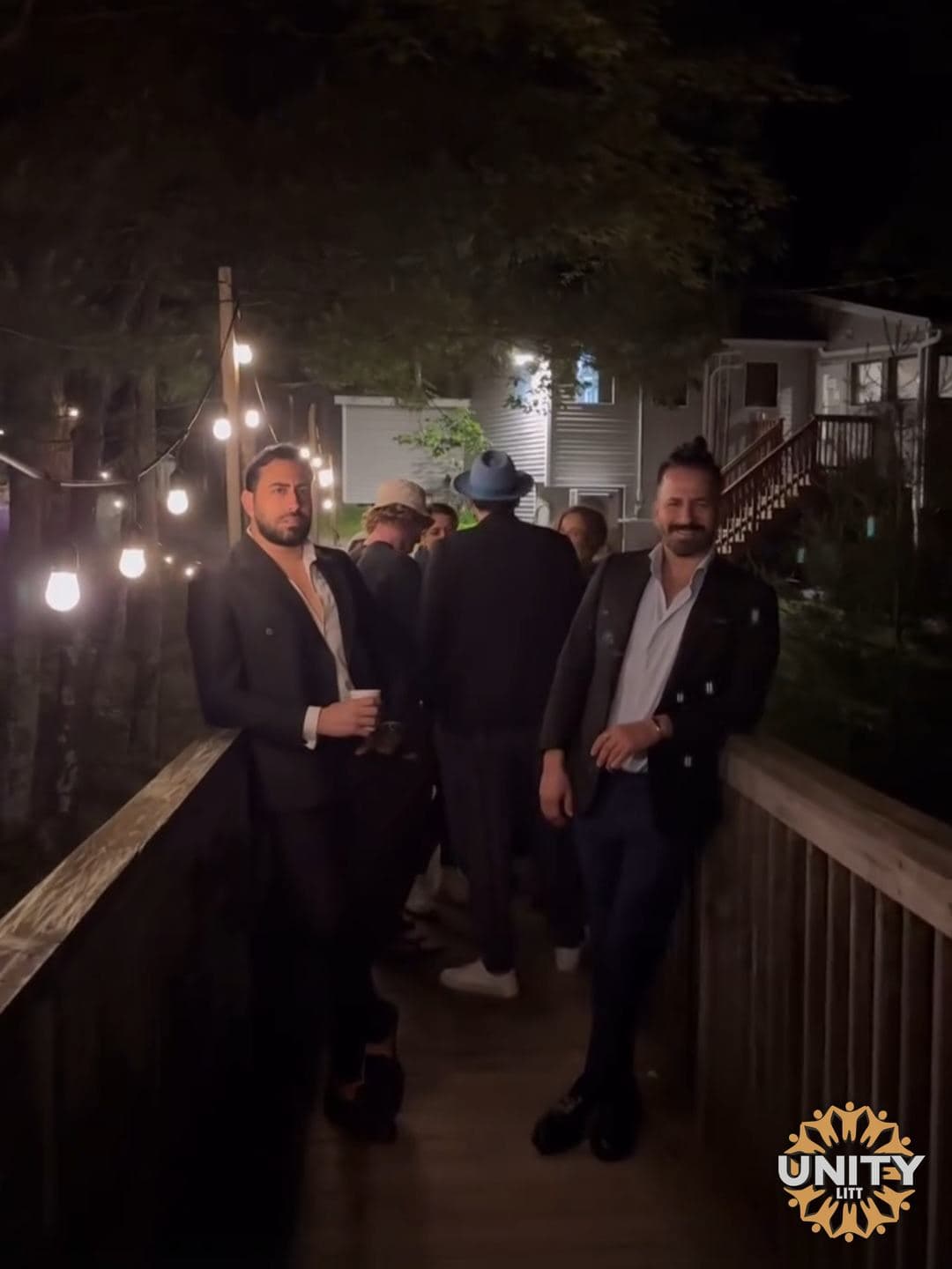 People standing and talking on the lit boardwalk at night