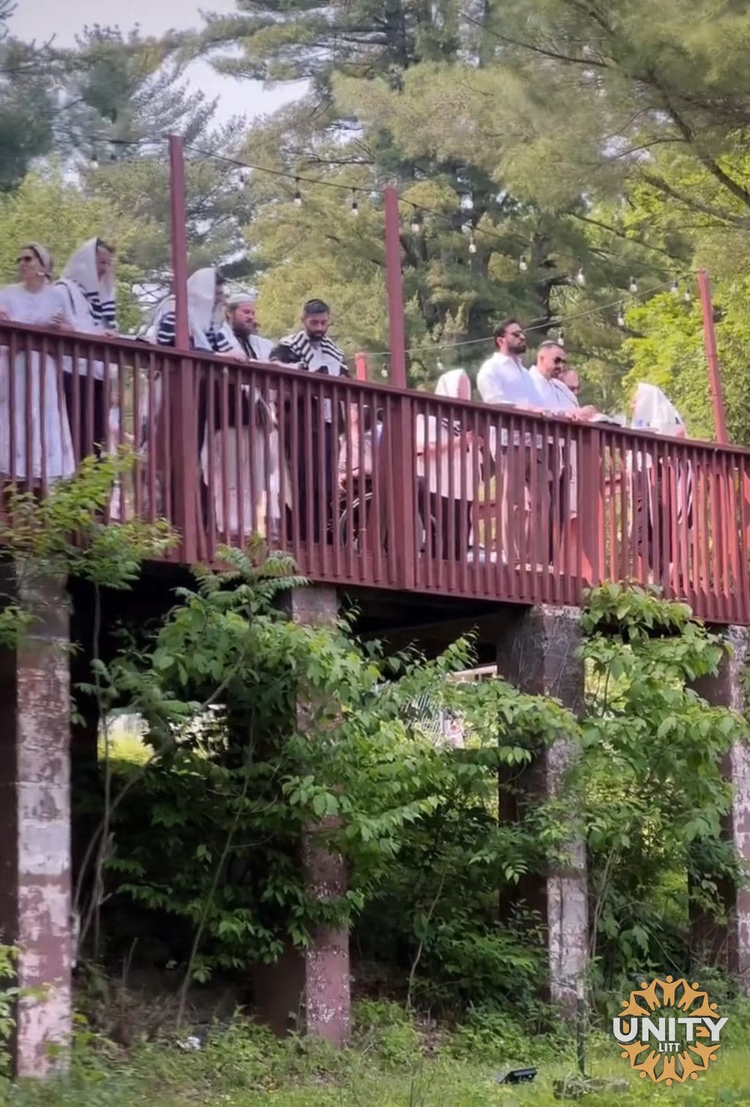 The wooden bridge seen through the trees, people crossing above the water