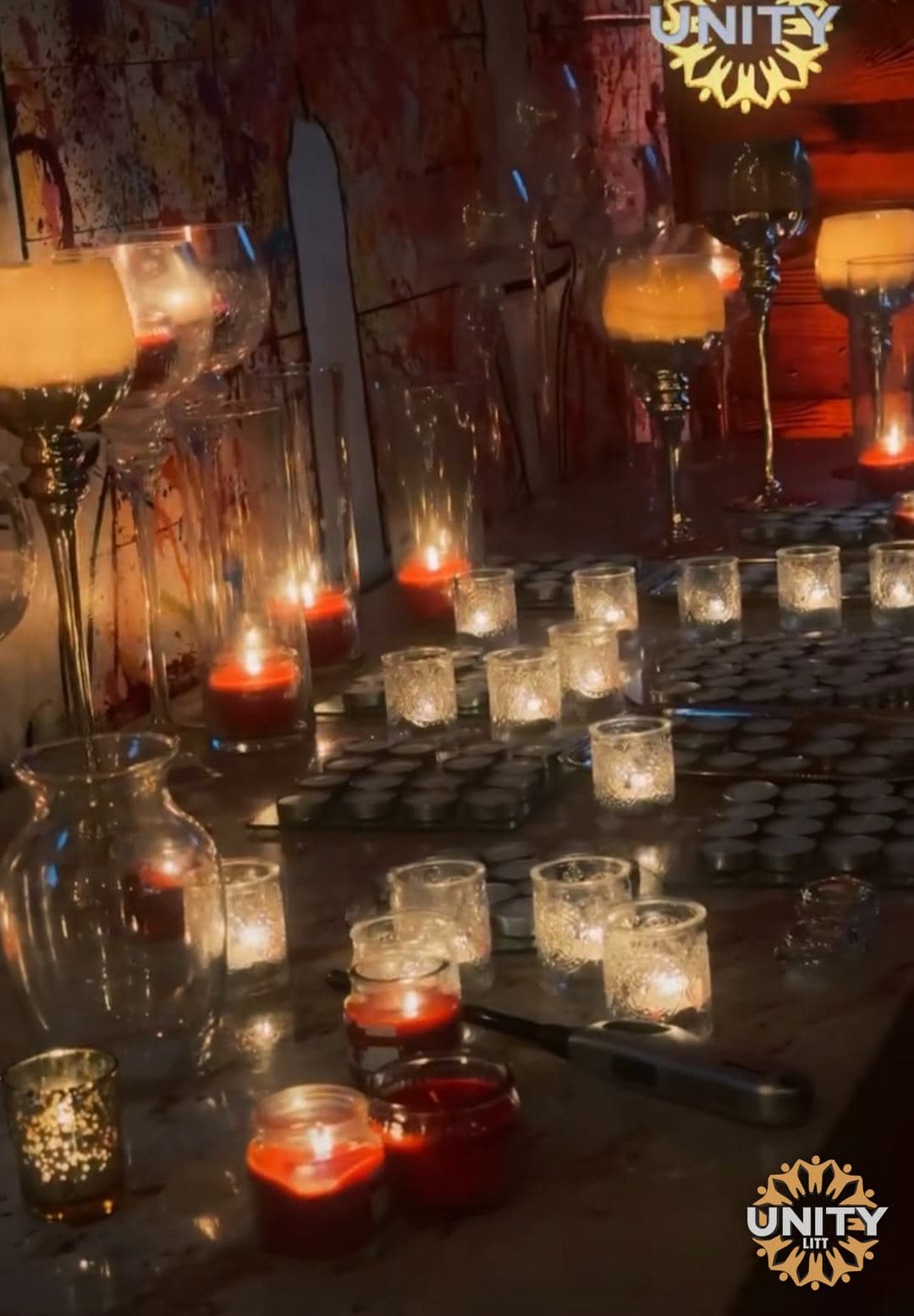 Dozens of small candles in glass holders across a table