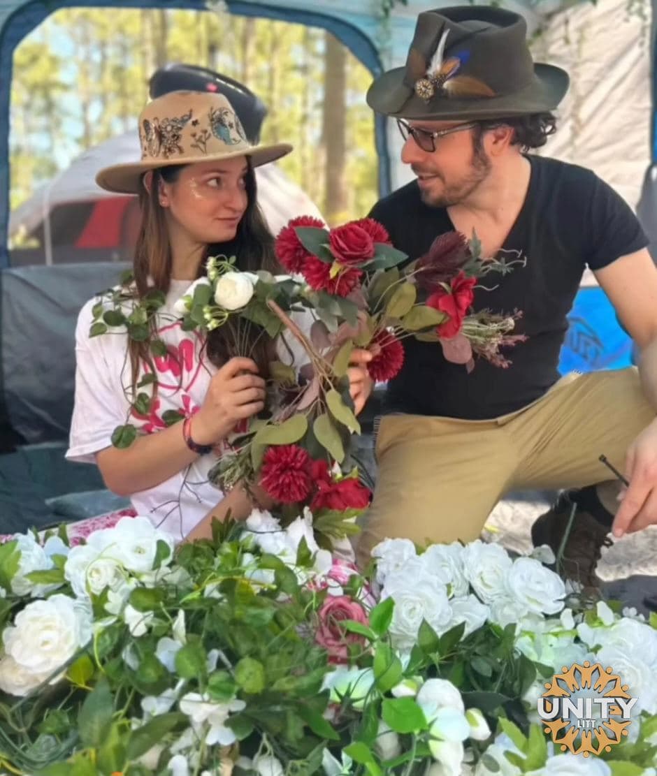 Two people crouched beside buckets of red and white roses