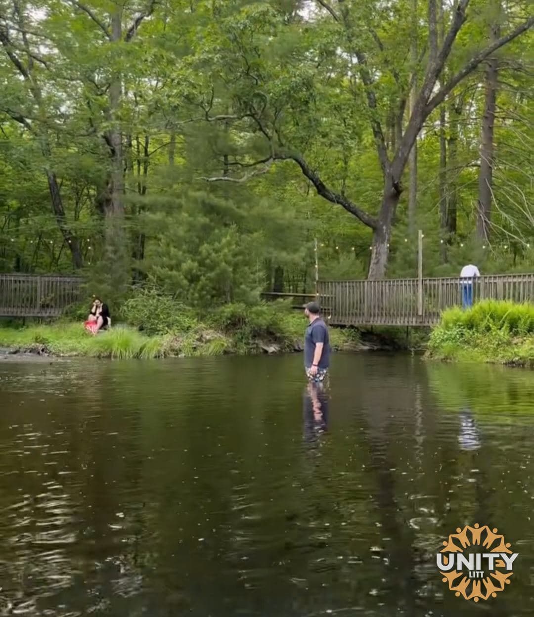 Someone standing quietly in the creek, trees closing overhead