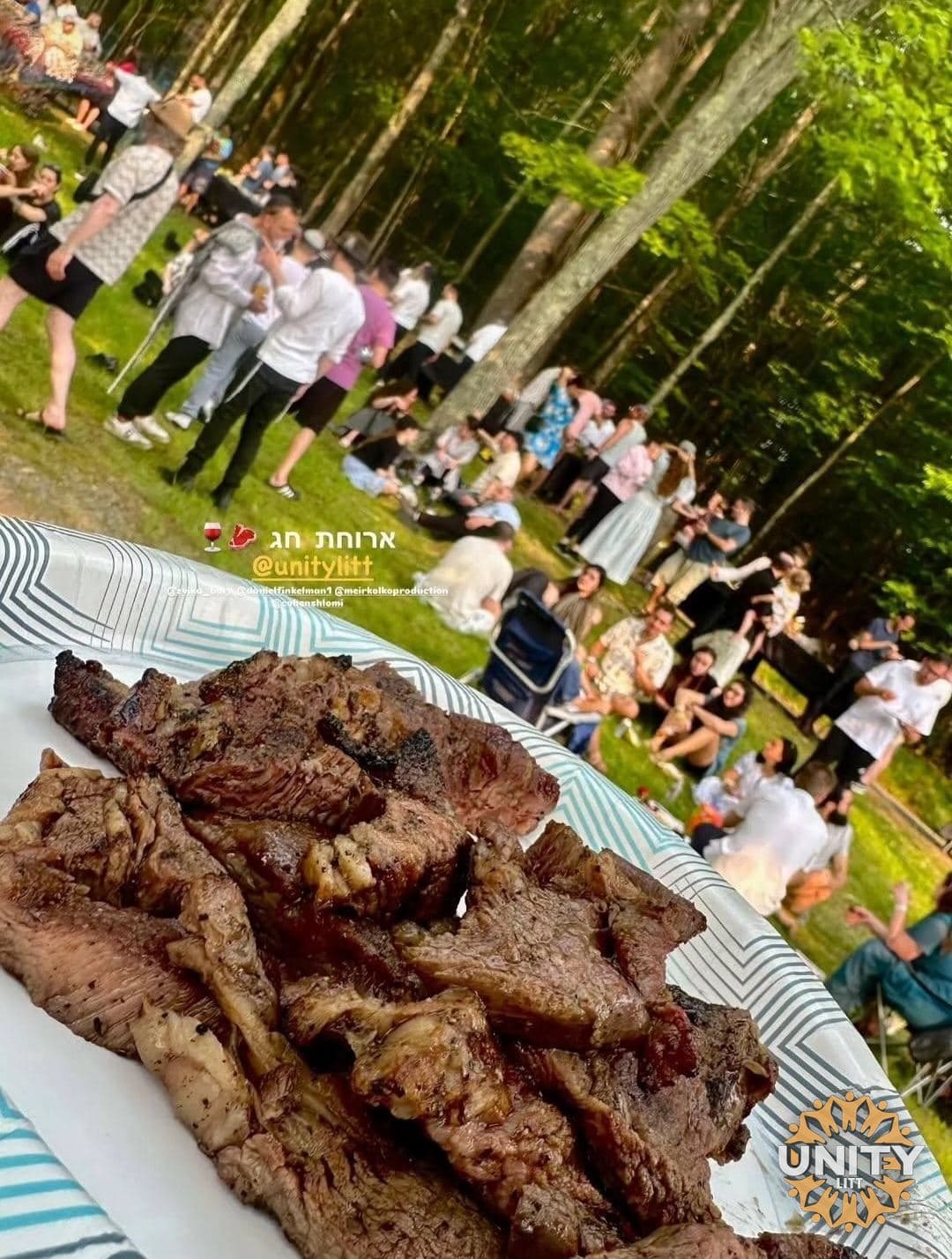 A platter of food carried out to a crowd seated on the grass