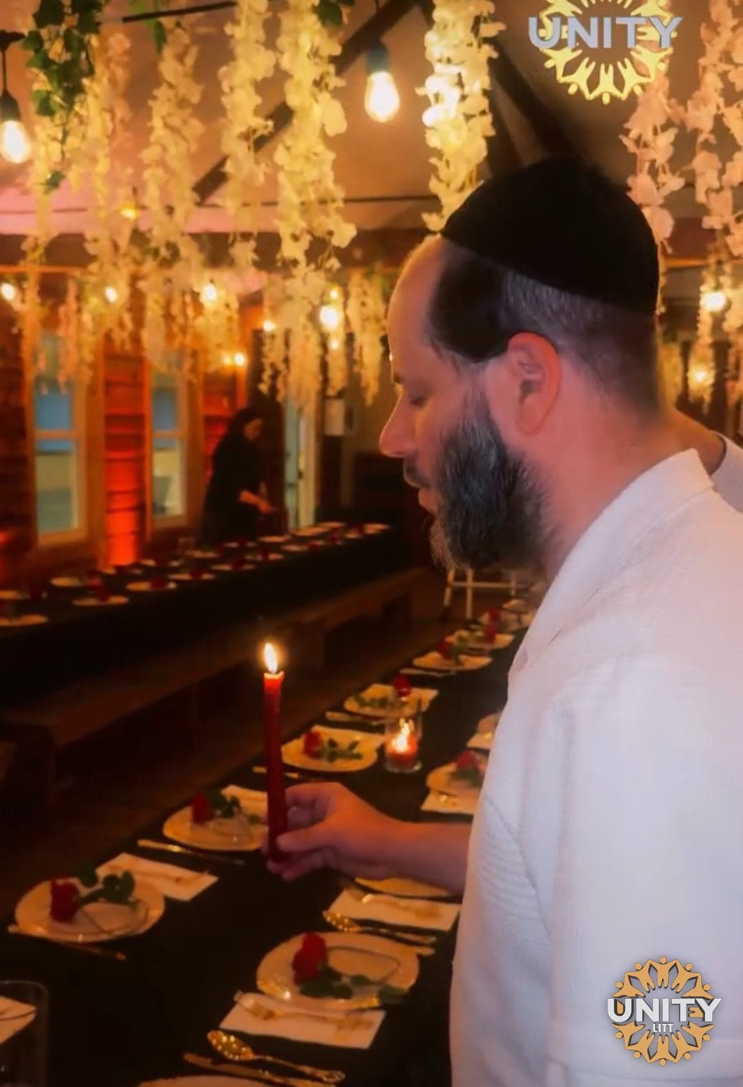A man making kiddush beside a candlelit table