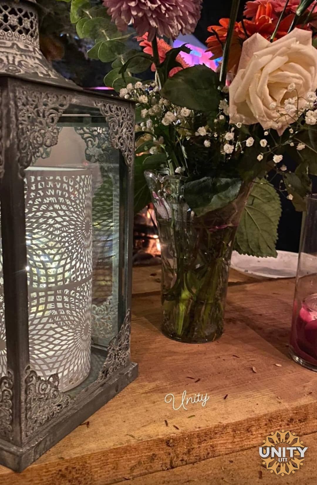 A lantern and a vase of flowers on a wooden table