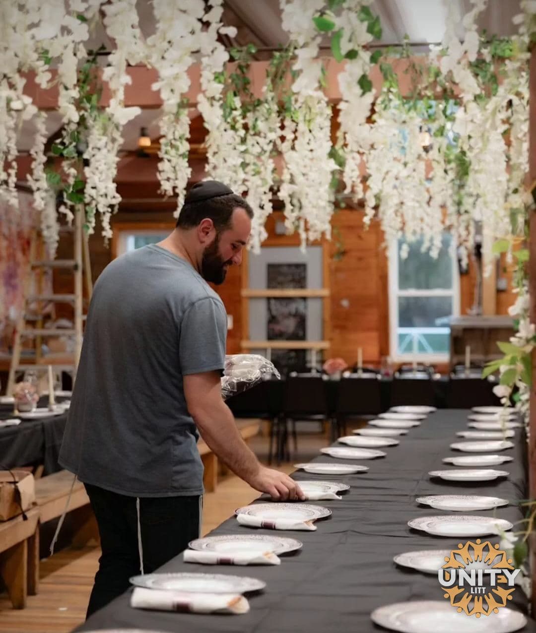 A volunteer laying out plates down a long table before a meal