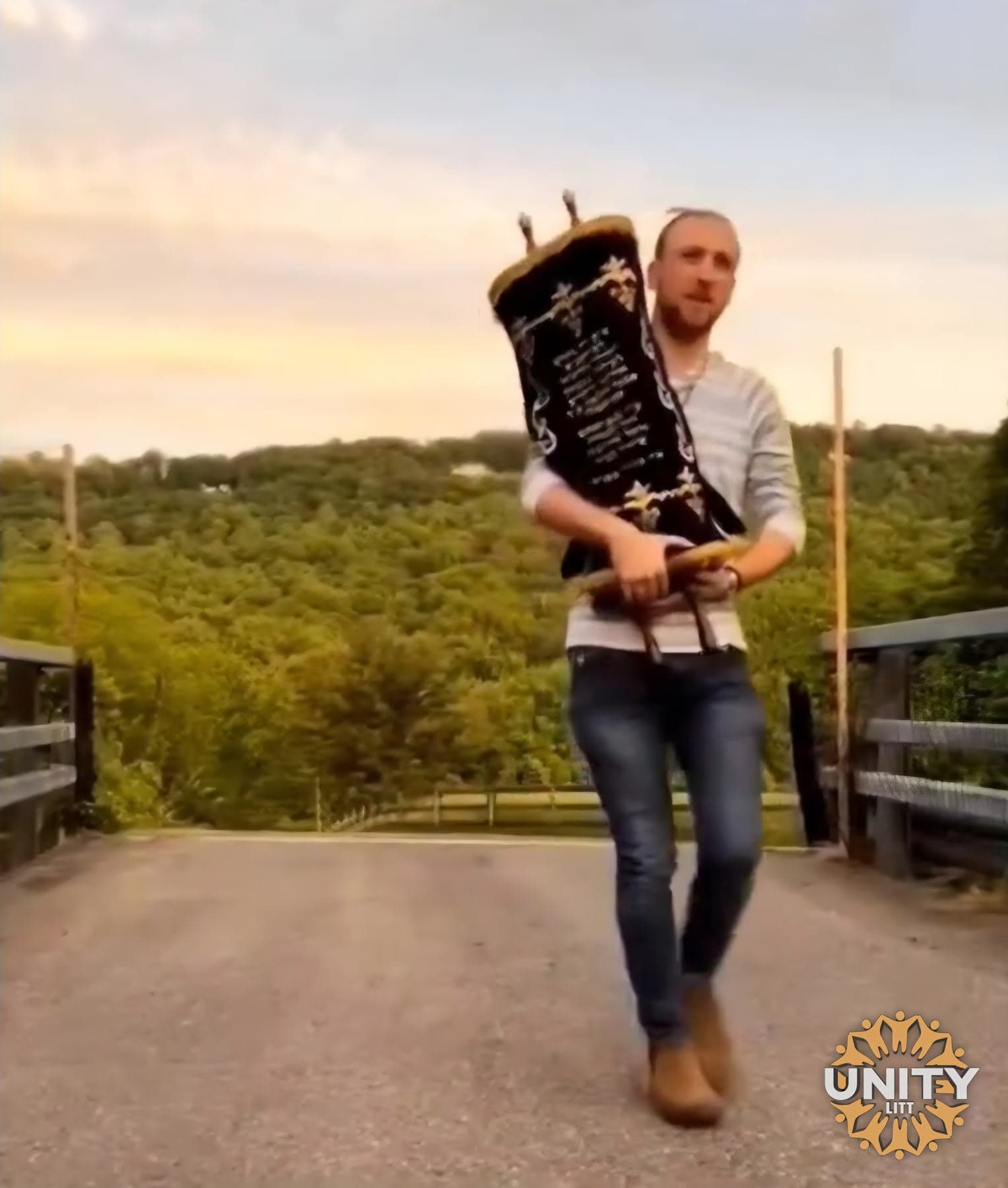 A man carrying a sefer Torah along the road at sunset