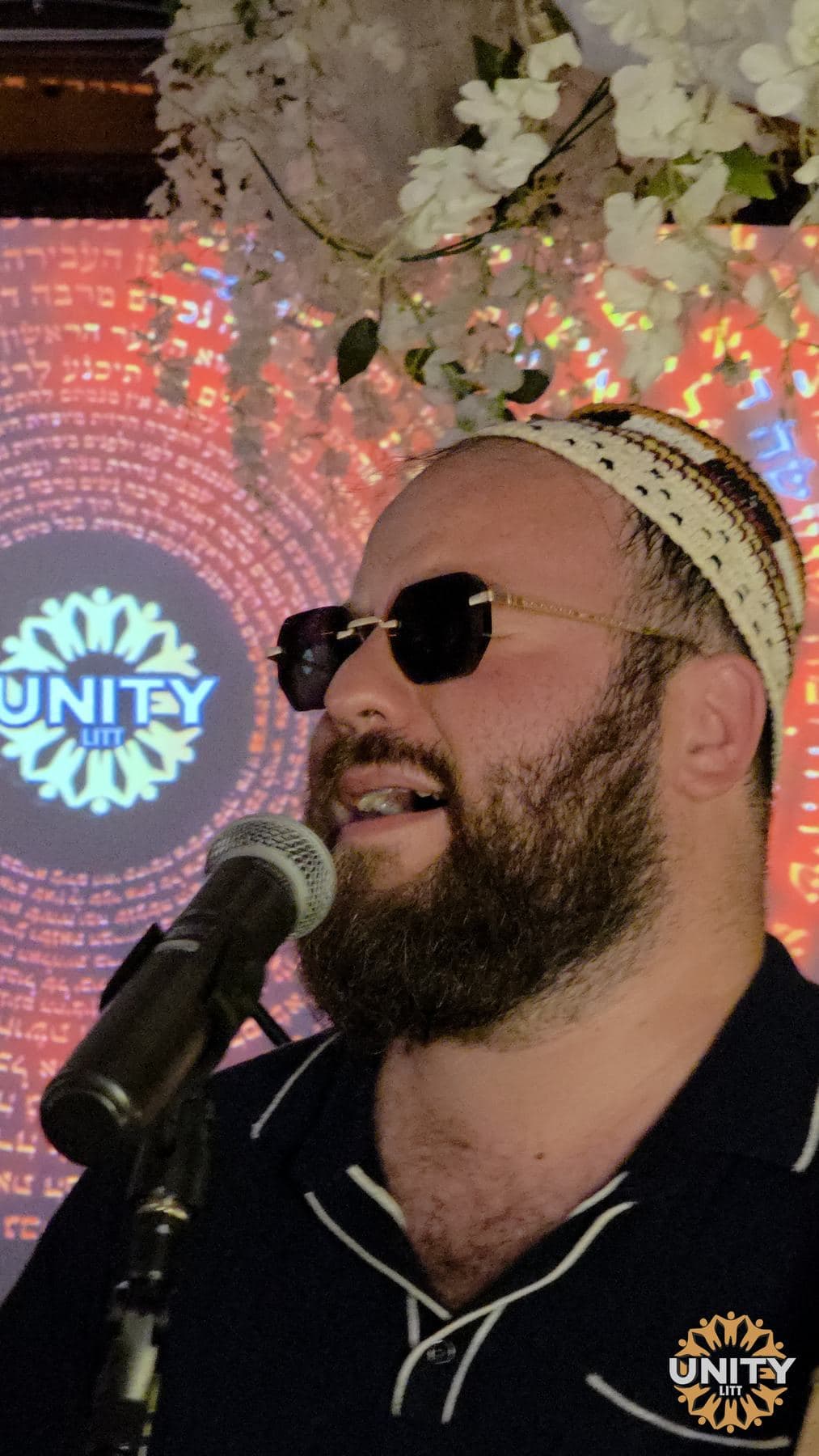 A singer close to the microphone, eyes shut, coloured light behind him
