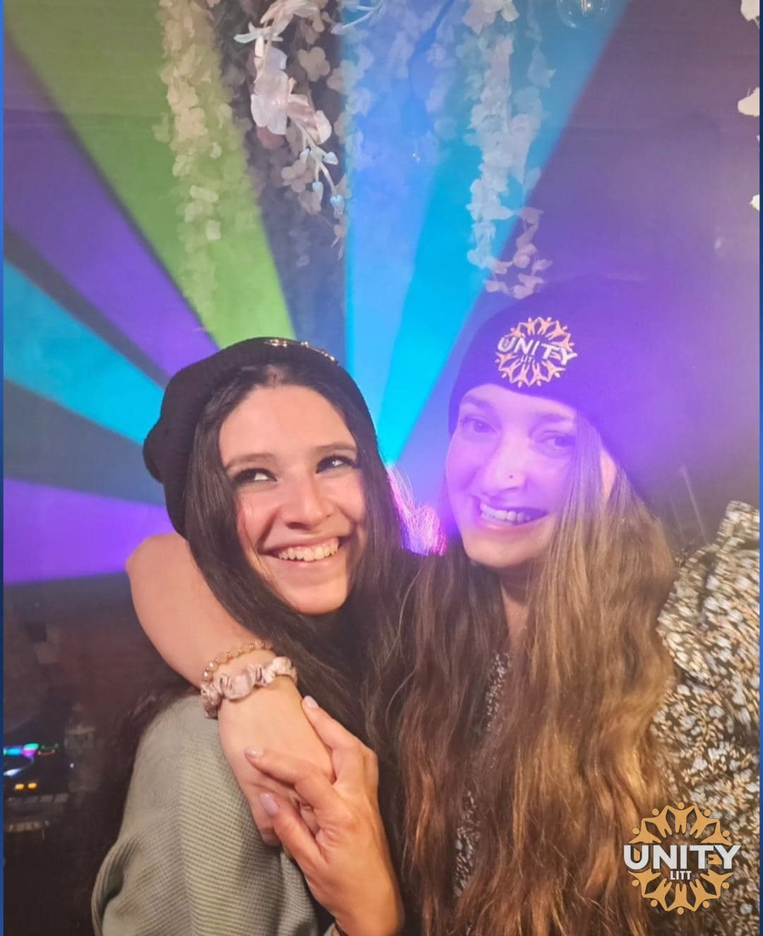 Two friends arm in arm on the dance floor under coloured lights