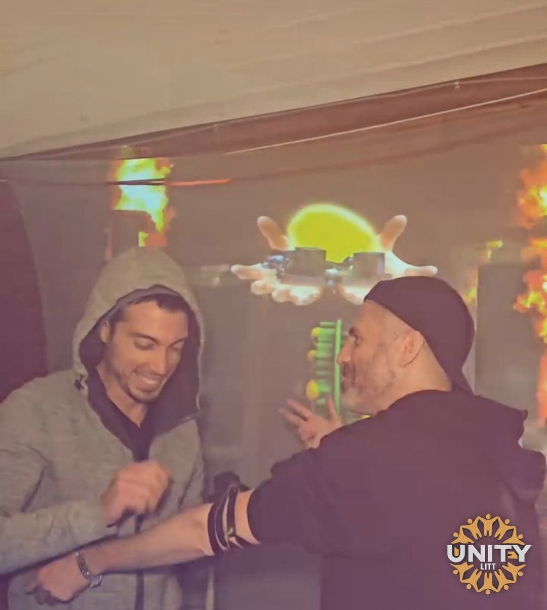 Two men laughing together, one with an arm around the other