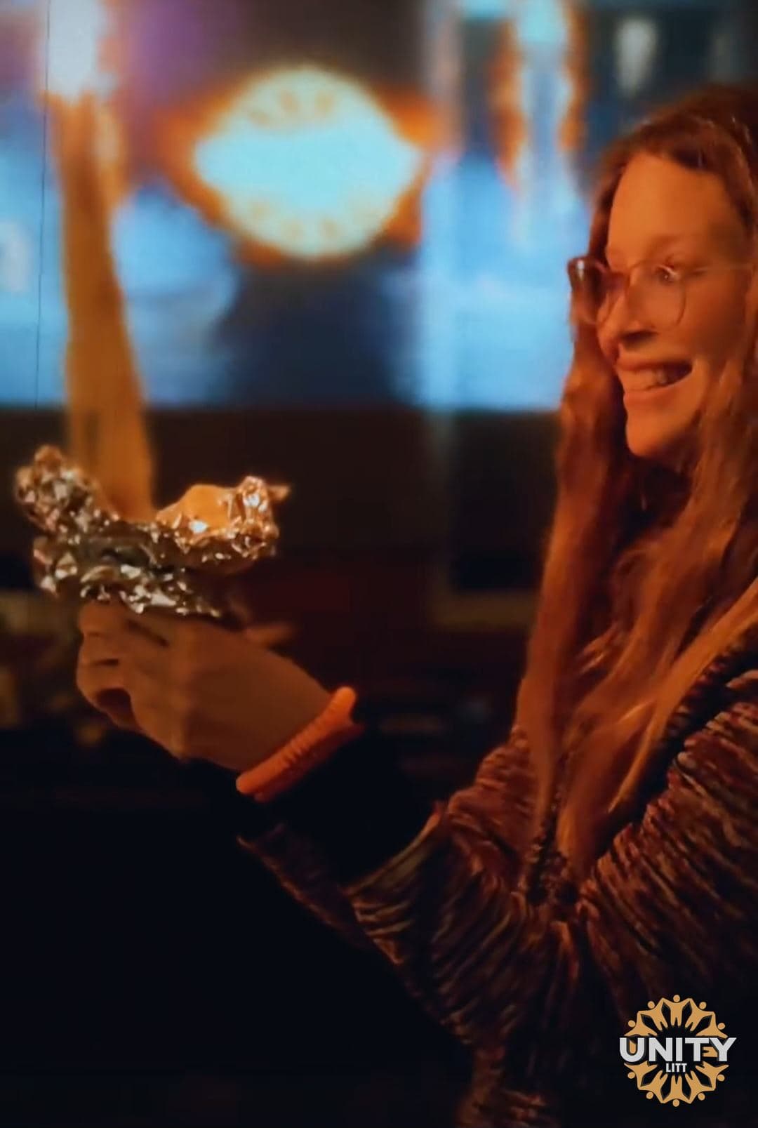 A woman lit by candlelight, smiling at something out of frame