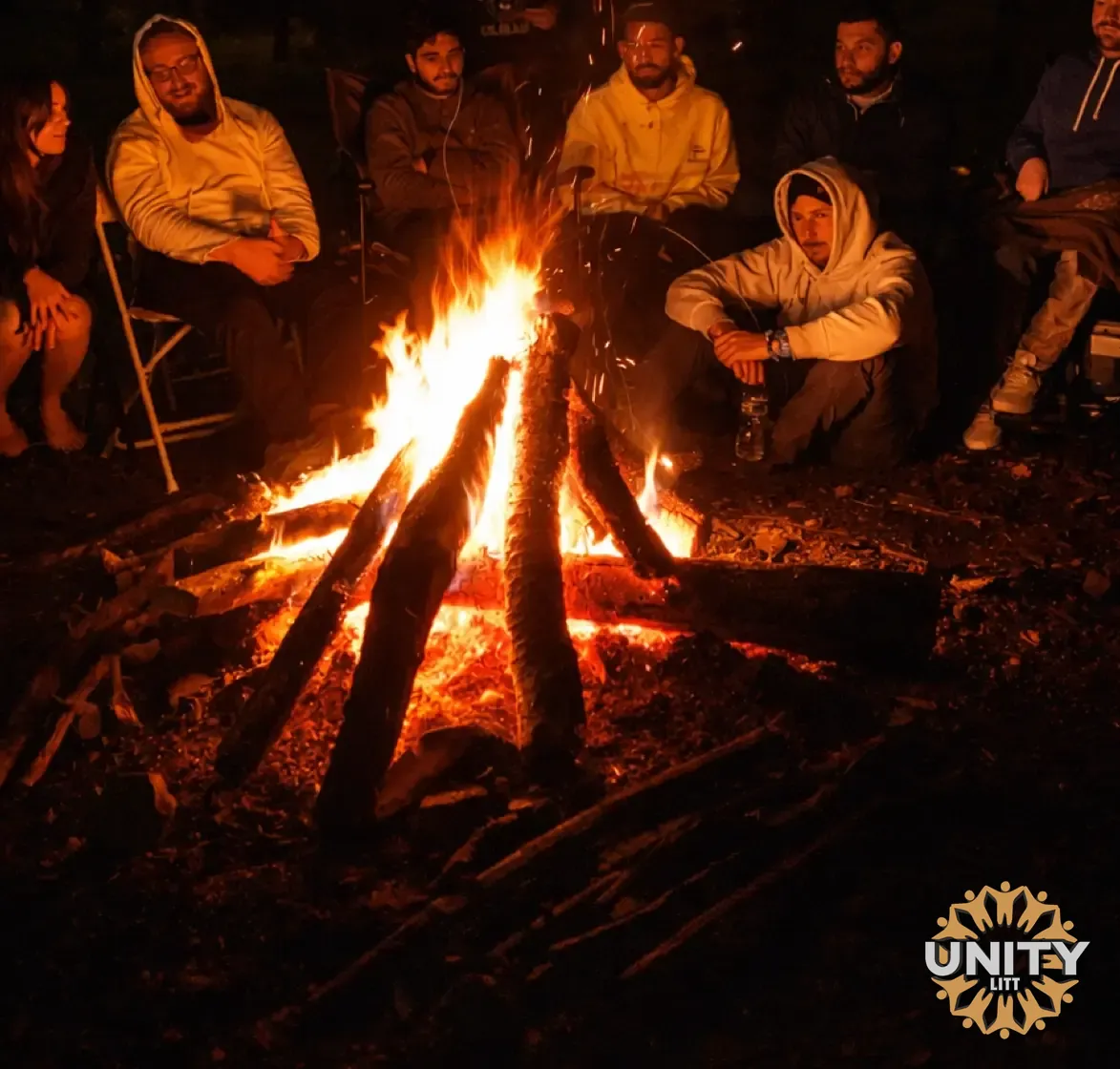 A bonfire burning at night, people gathered around it