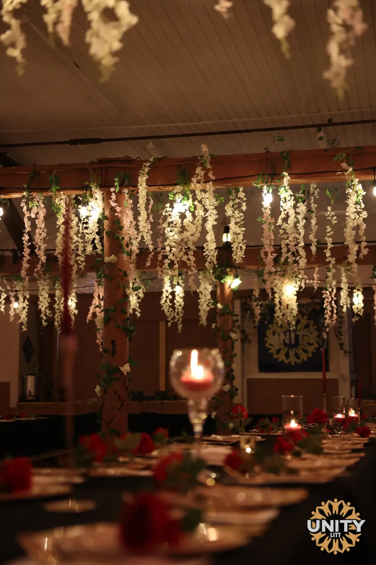 A dining room dressed for the holiday — flowers and warm lights hanging above long tables